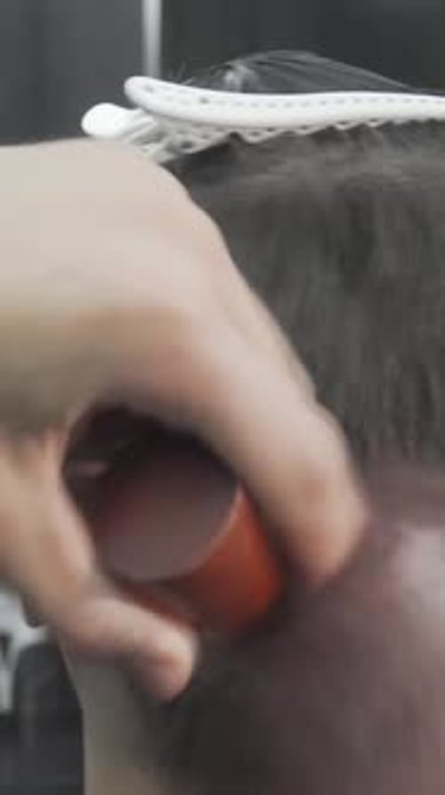 Barber Meticulously Brushing Away Hair From a Freshly Styled Client