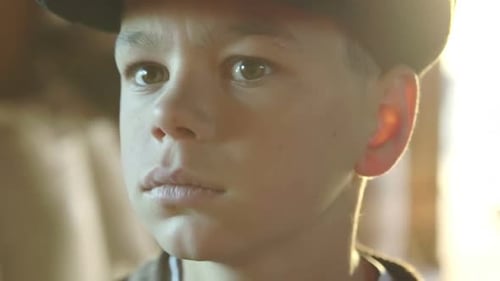 Sombrero triste, molesto, aburrido, preocupado e infeliz para un niño pequeño en primer plano a la luz del sol