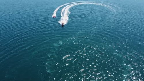 Aerial: Tourists enjoying a bumpy, fun ride towed by motorboat in sea