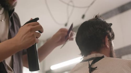 Hairdresser Spraying and Combing Hair of Client in Barbershop