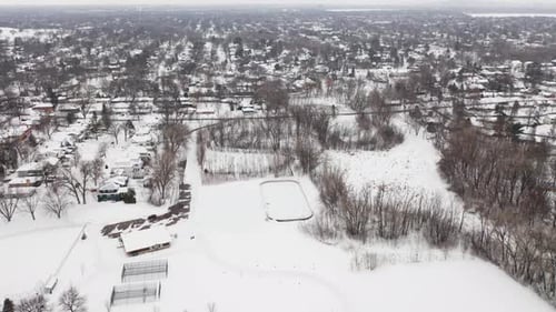 Aerial, community skating rink in a snow covered suburb neighborhood during winter