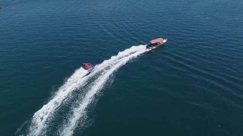 Drone follows tourists having a fun, wet day towed on raft by boat