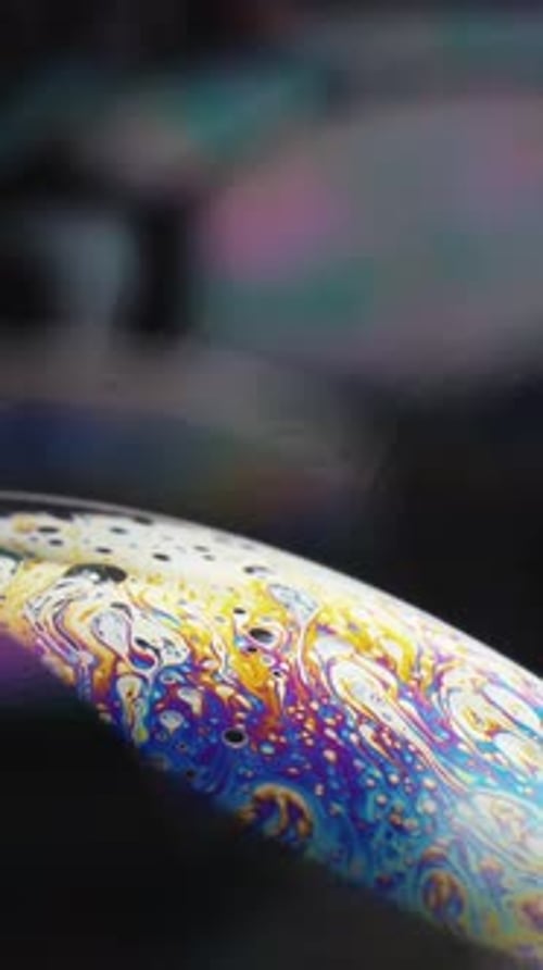 large soap bubbles and multi-colored patterns, reflected in bubbles, close-up. Vertical video.