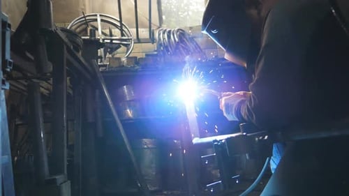 Worker in Protective Mask Welding Metal Construction at Industrial Production