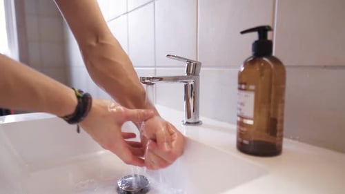 Person Washing Hands with Soap at Sink