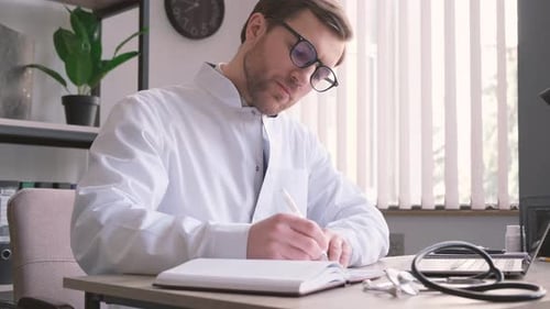 Concentrated Professional Young Doctor and Uniform is Working in His Office Doing Paperwork
