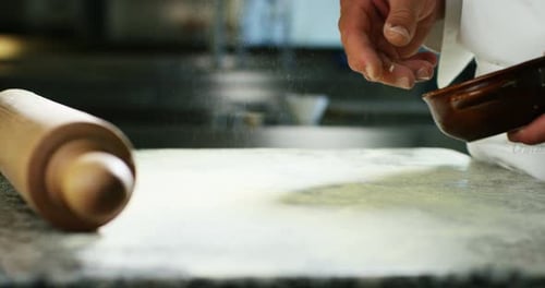 An experienced chef in a professional kitchen prepares the dough with flour to make the bio Italia