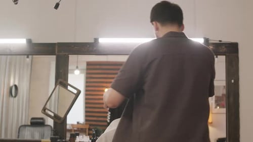Young Barber Giving Haircut during Workday in Hairdressing Salon