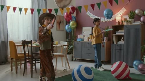 Dois meninos brincalhões pulando balões com espadas de brinquedo durante a celebração do aniversário