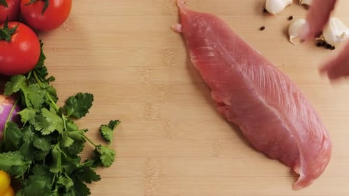 Man Slicing Raw Turkey or Chicken Meat Fillet on Oak Cutting Board Closeup Cooking with Knife on