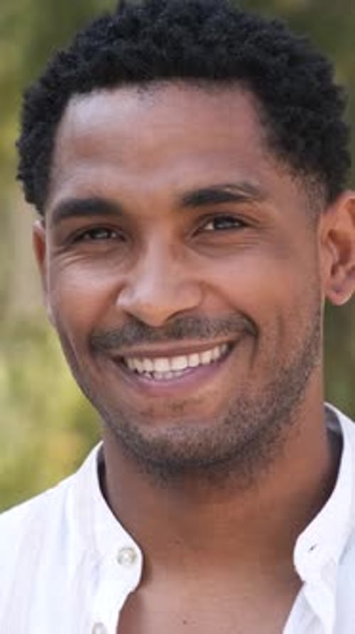 Primer plano de un joven feliz mirando a la cámara durante el día