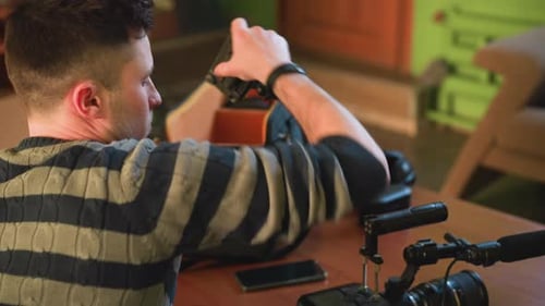 Person Sitting at Table Reaching Into Camera Equipment Bag