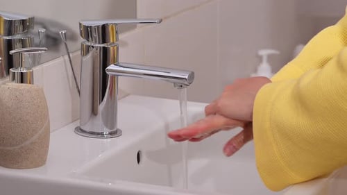 Woman takes soap from dispenser and washing hands.