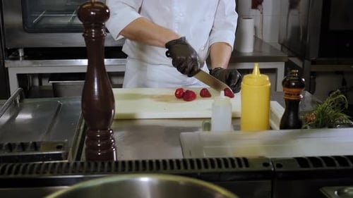 A Chef Cutting Strawberries on a Cutting Board in a Professional Kitchen