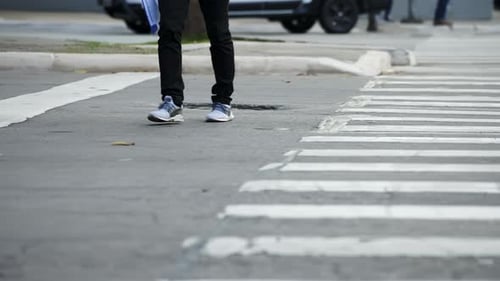 Pedestrians crossing a street by the crosswalk of a big city in daylight filmed in slow motion in 4K