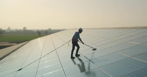Cinematic shot of maintenance assistance technical worker in uniform is cleaning photovoltaic sola