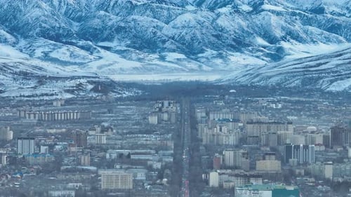 City skyline bathed in golden light against massive snow covered mountains