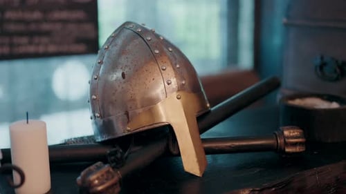 Medieval helmet with crossed weapons on display in dimly lit room
