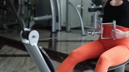 A Strong Girl Trains Her Back Muscles on a Horizontal Simulator in a Light Gym
