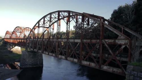 Old and rusty bridge with train line over a disused river