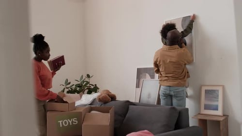 Família desempacotando coisas e pendurando pinturas após a mudança