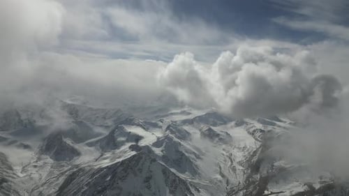 El paisaje montañoso nevado revela picos dramáticos y nubes cambiantes que muestran la belleza de la naturaleza