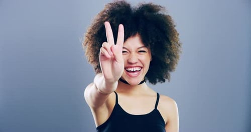 4k video footage a young woman showing a peace sign against a grey background