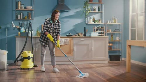 A Young Beautiful Woman Washes the Floor with a Mop in the Kitchen