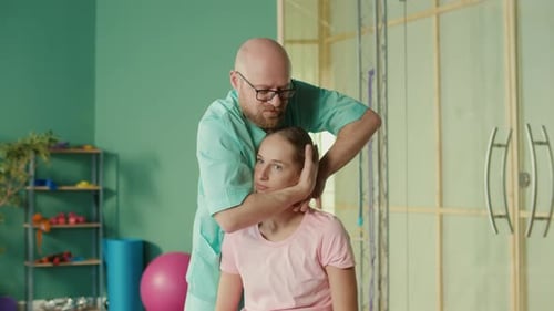 Physiotherapist Helps Girl to Do Exercises to Relieve Pain in Rehab Clinic