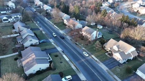 Traffic on street through residential community in USA during winter season. Descending aerial view
