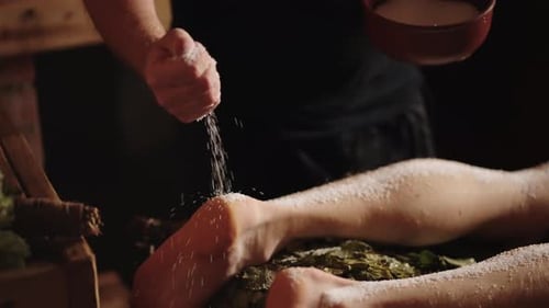 Vista de perto das mãos do massagista derramando sal marinho na pele do cliente no centro de spa Massagem com sal