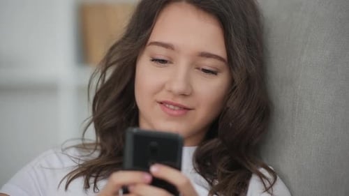 Close up view of cute positive young girl that using smartphone
