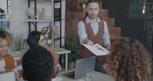 Executivo da empresa entregando documentos a um grupo de funcionários durante reunião de negócios no escritório