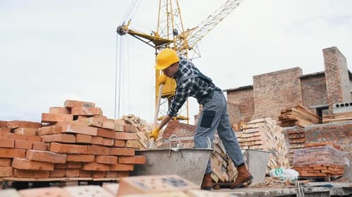 Uses shovel. Construction worker in uniform and safety equipment have job on building