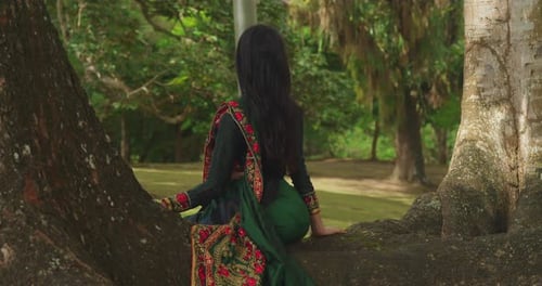 In the Caribbean, a young girl wearing traditional Indian clothes enjoys a day at a tropical park.