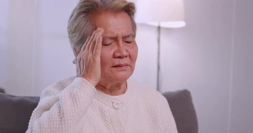 Anciana asiática con migraña. Mujer mayor que sufre de dolor de cabeza.