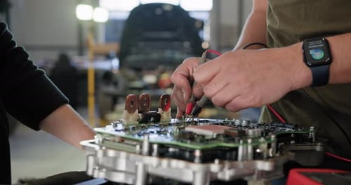 Mechanic Inspecting Electric Car Engine In Workshop