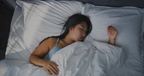 Young Girl Sleeping in Bed in Bright Sunfilled Bedroom