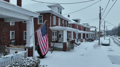 American Flag in front of house in american neighborhood. Snow capped street after snowstorm at nigh