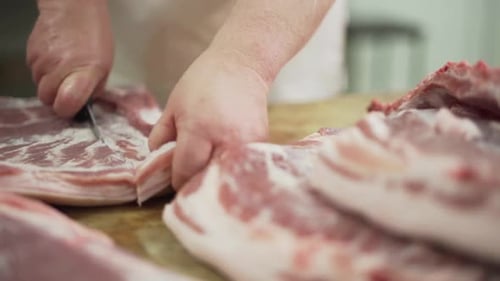 Butchers male Hands cuts fresh raw Pork Meat on Table with kitchen knife. Slow motion.