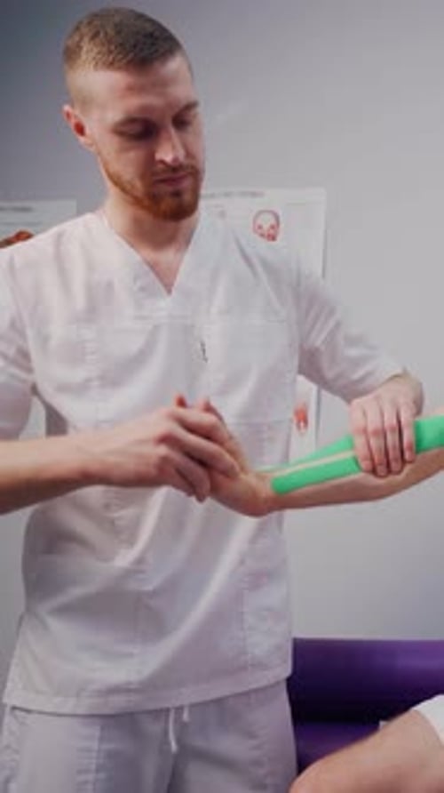 Doctor Applying Kinesio Tapes to a Boxer Athlete Patient's Arm After a Fight The Therapist