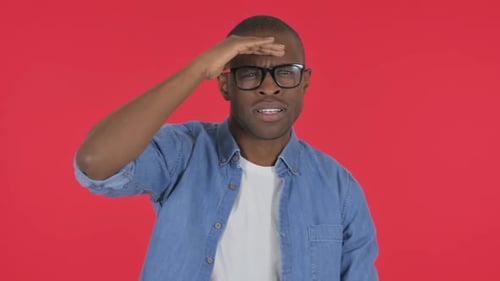 Hombre africano casual que busca una nueva oportunidad sobre fondo rojo, retrato