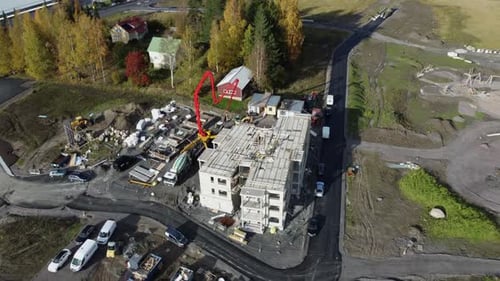 Workers use heavy pump boom to get concrete into construction building