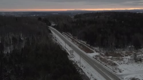 Car Driving On Snowy Highway With Bare Trees On A Winter Sunrise - aerial drone, tilt down