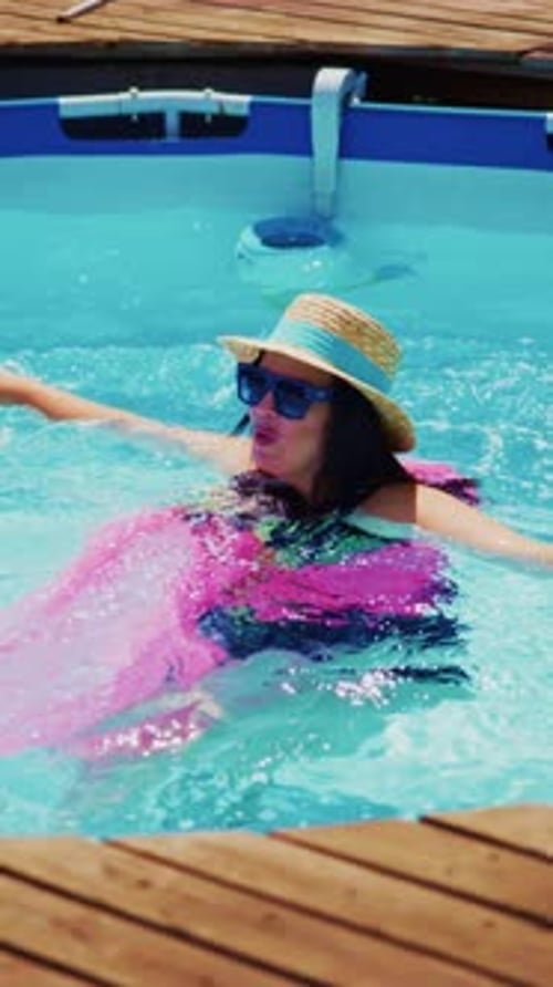 Joyful Moments of Summer A Woman Enjoys Swimming in a Pool with a Colorful Float Sporting Sunglasses