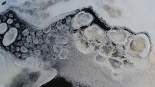 Aerial view of ice shape formations float near frozen lake ice sheet