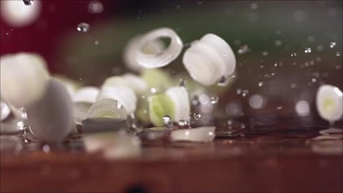 Tombe d'oignons verts frais hachés sur une planche à découper au ralenti