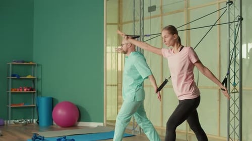 Sportswoman with a Personal Trainer Does Exercise with the Help of Expanders