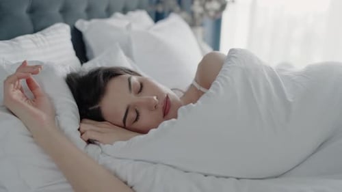 Peaceful Woman Sleeping Comfortably in Bed with White Sheets in Cozy Bedroom