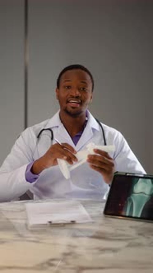 Male orthopedic doctor showing foot skeleton, ankle joint anatomy model explain for patient